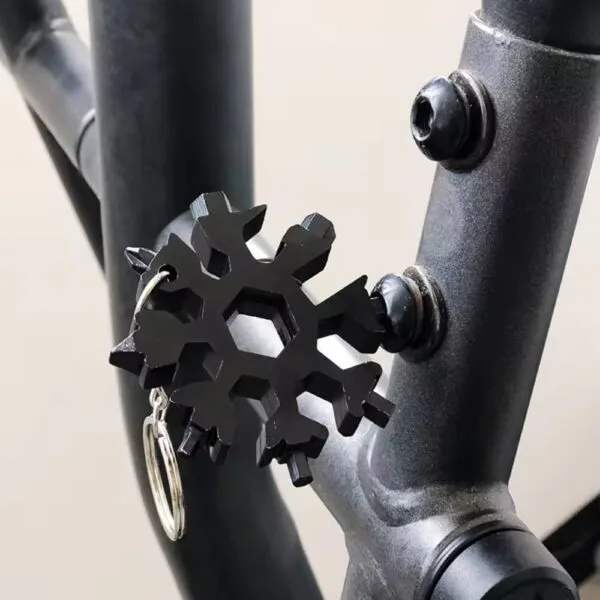 Black Snowflake Multitool Keychain used to tighten a bolt