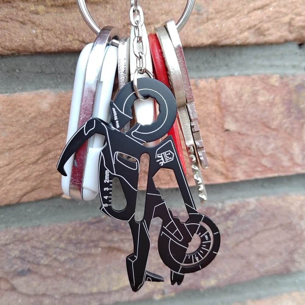 Motorcycle keychain multitool on a keyring in front of a brick wall